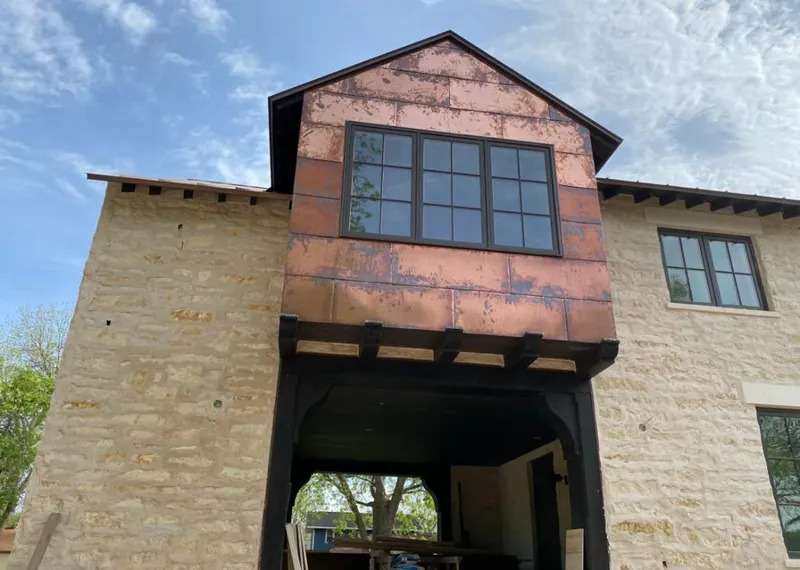 Copper metal panel facade on a stone building for Skylight Installation in Storm Lake